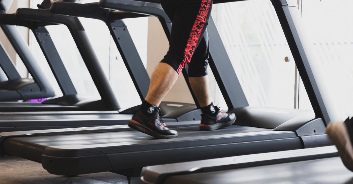 A person walking on a treadmill in a modern gym setting, focusing on fitness.